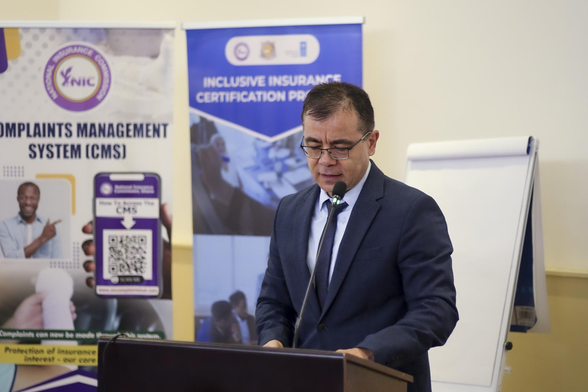a man in a suit standing in front of a laptop