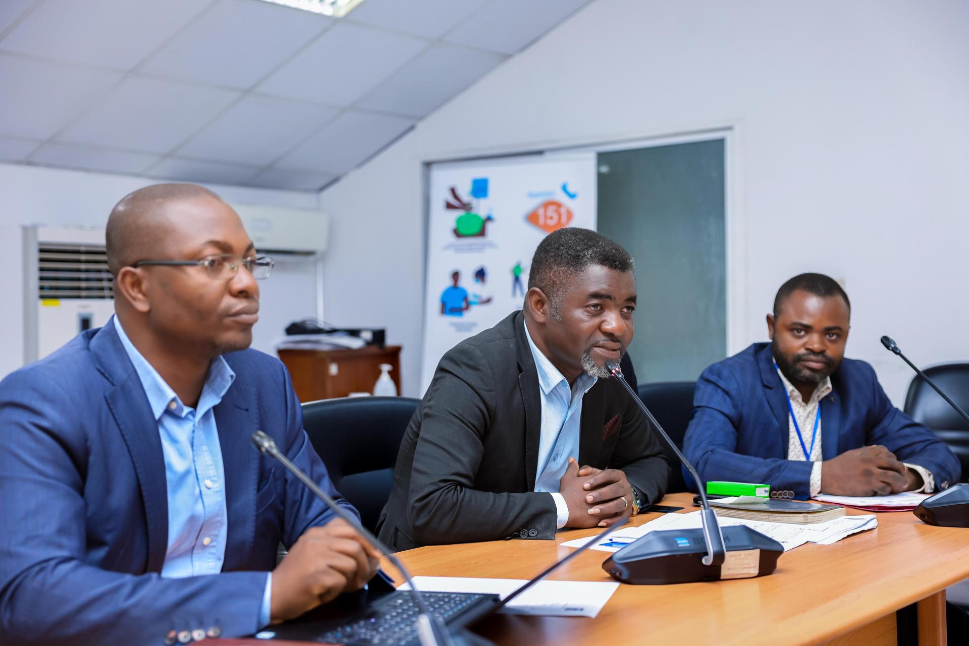 un groupe de personnes assises à un bureau et regardant un ordinateur portable