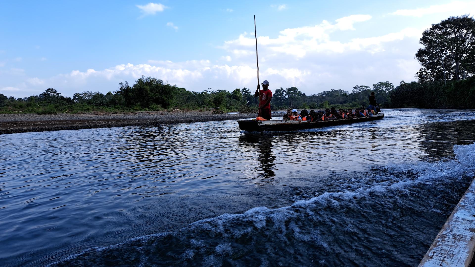 a boat floating along a river next to a body of water