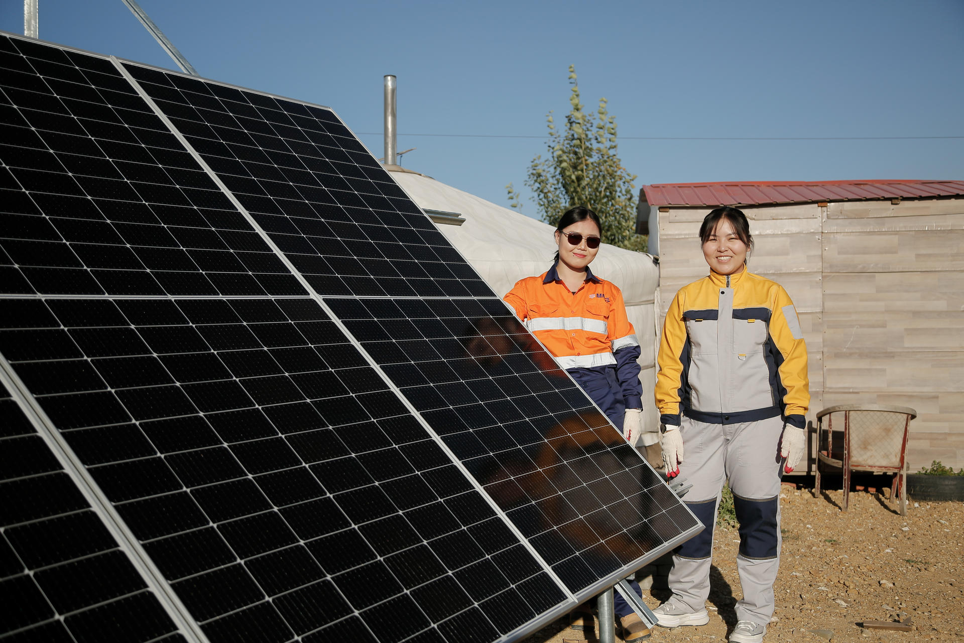 two women standing next to a solar panel