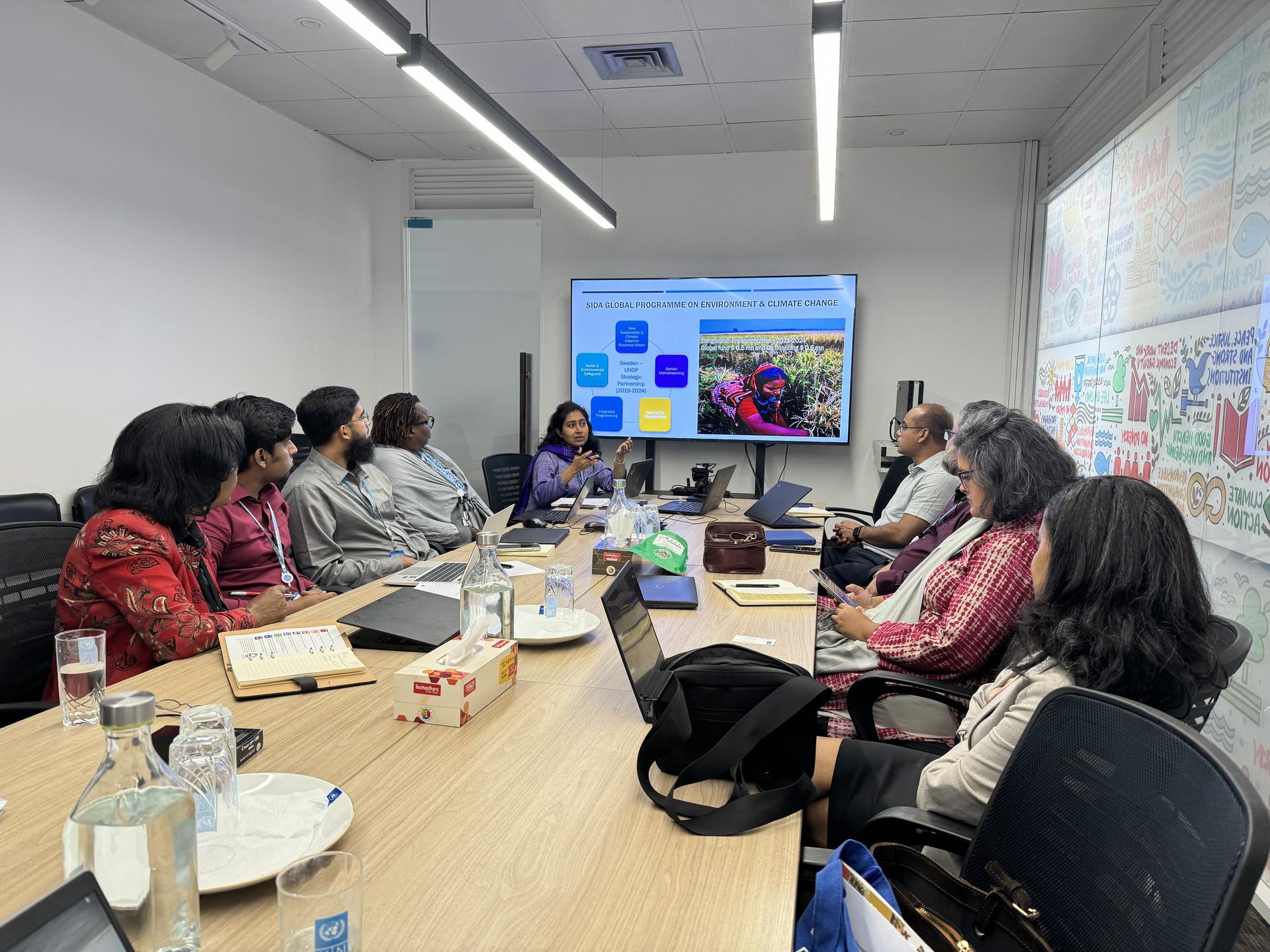 a group of people sitting at a table with a laptop in a room