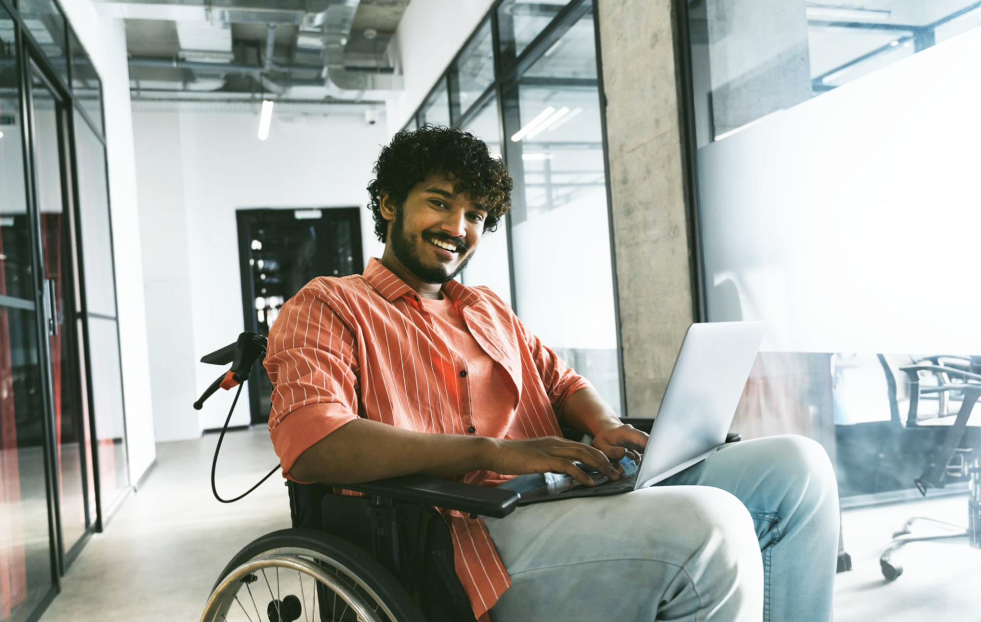 a man sitting in a wheelchair, using a laptop 