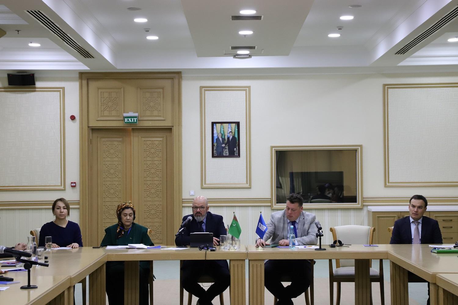 Group of individuals seated at a conference table, engaged in discussion in a formal setting.
