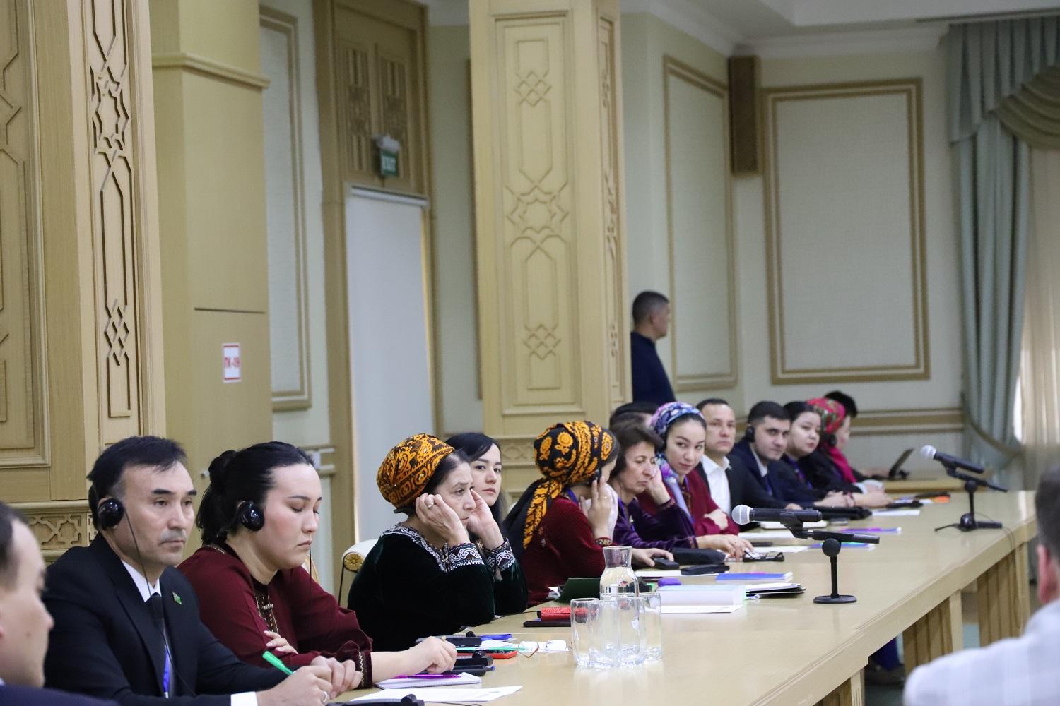 A diverse group of people seated at a conference table in an ornate room.