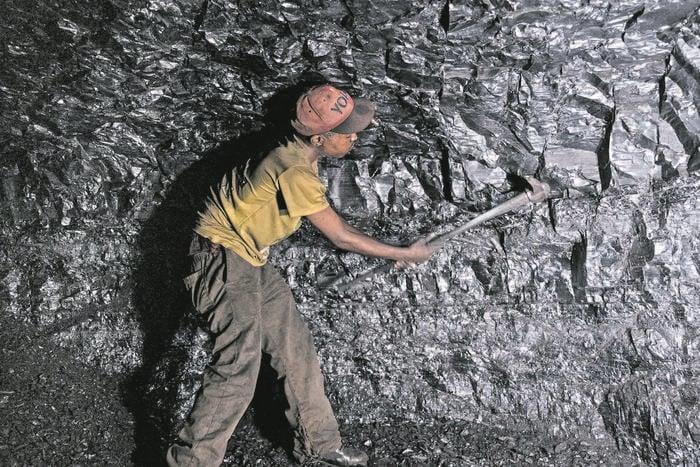 a man standing mining a rock