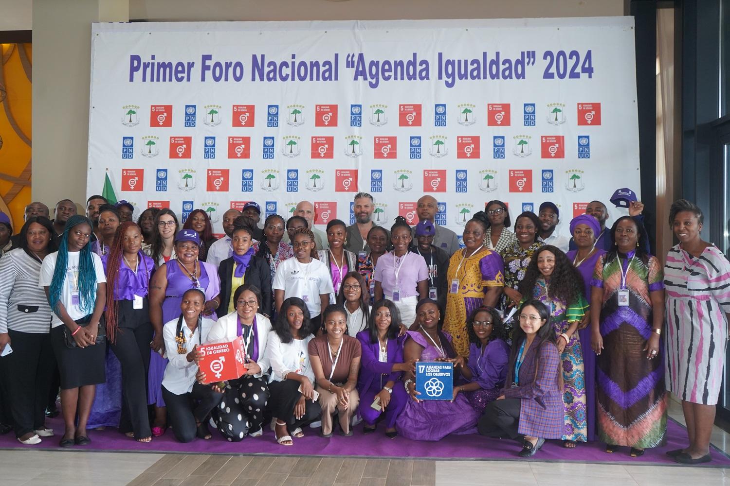 Group of diverse individuals posing together in formal attire at an event backdrop.