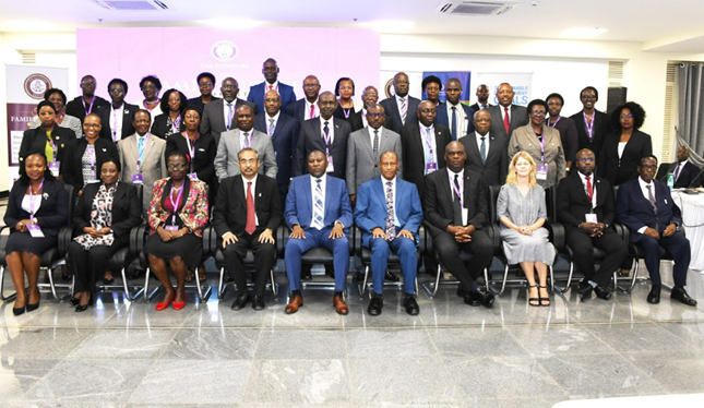 Group photo of diverse individuals in formal attire, seated and standing in a conference setting.