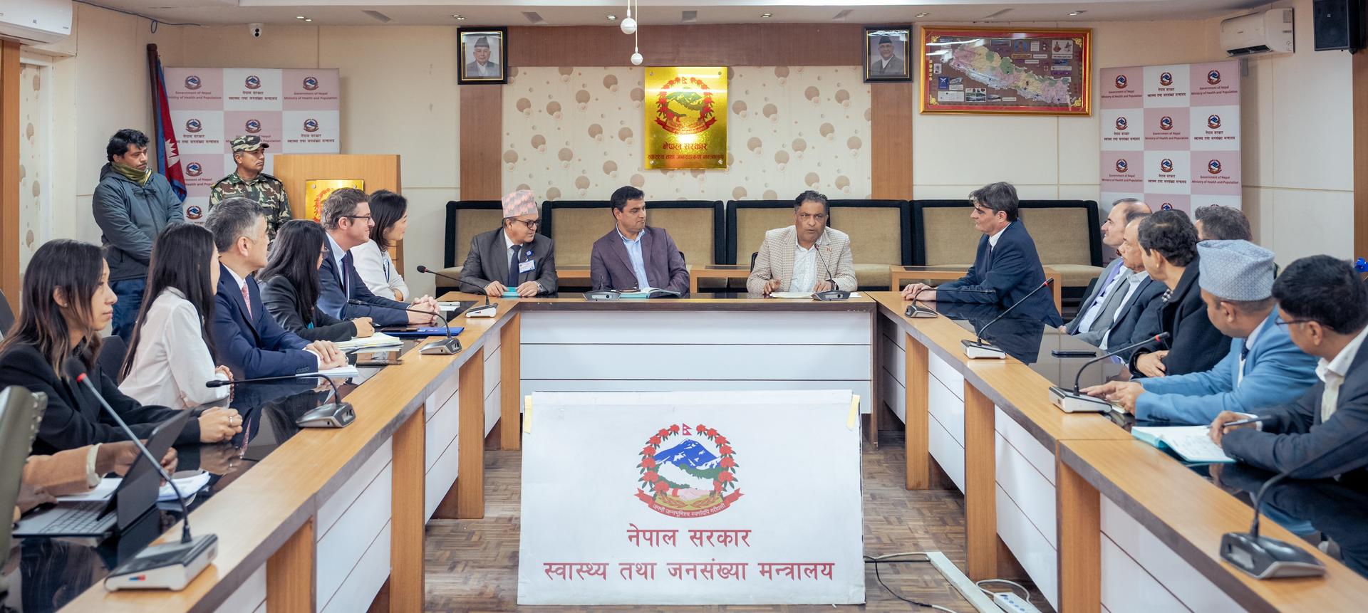 A formal meeting in a conference room with officials seated around a table.