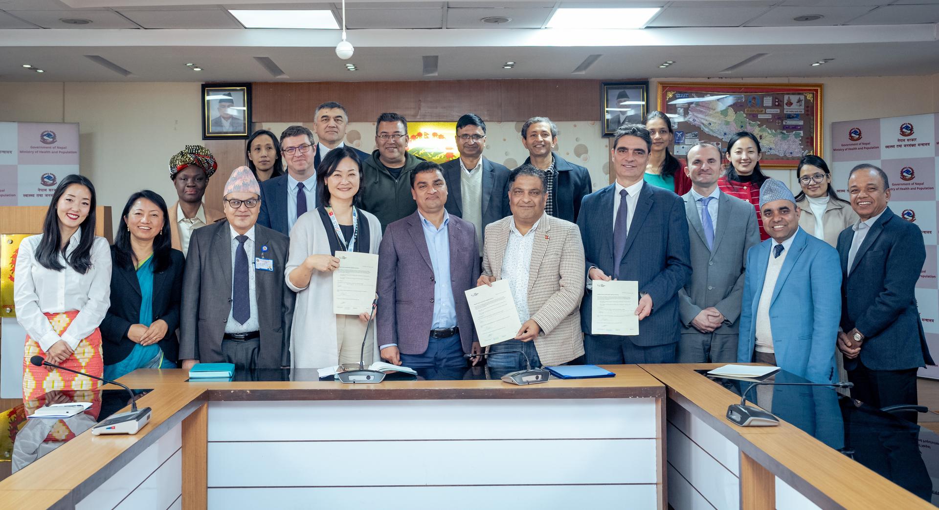 Group of people posing with signed documents in a conference room.