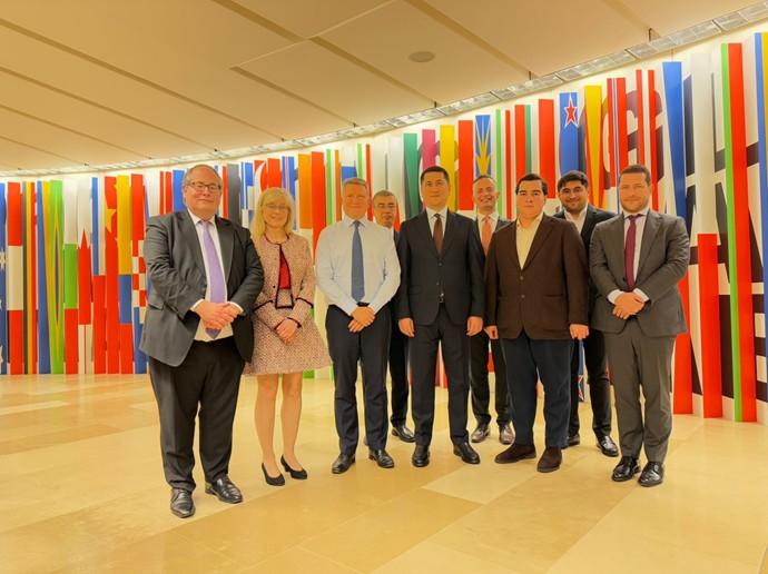 Group of people posing together in front of colorful flags on display.