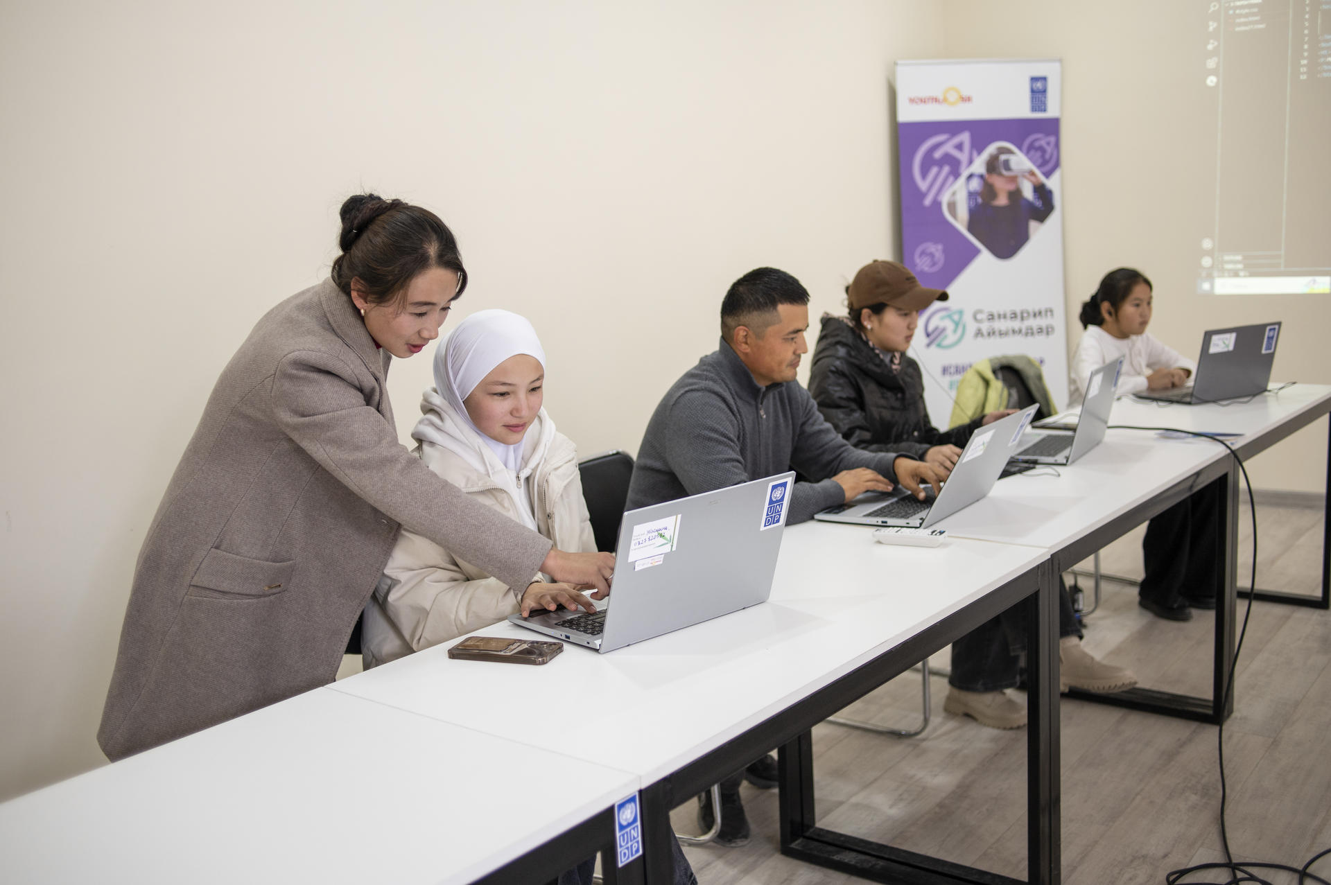 A group of individuals working on laptops at a conference table, focused on their tasks.