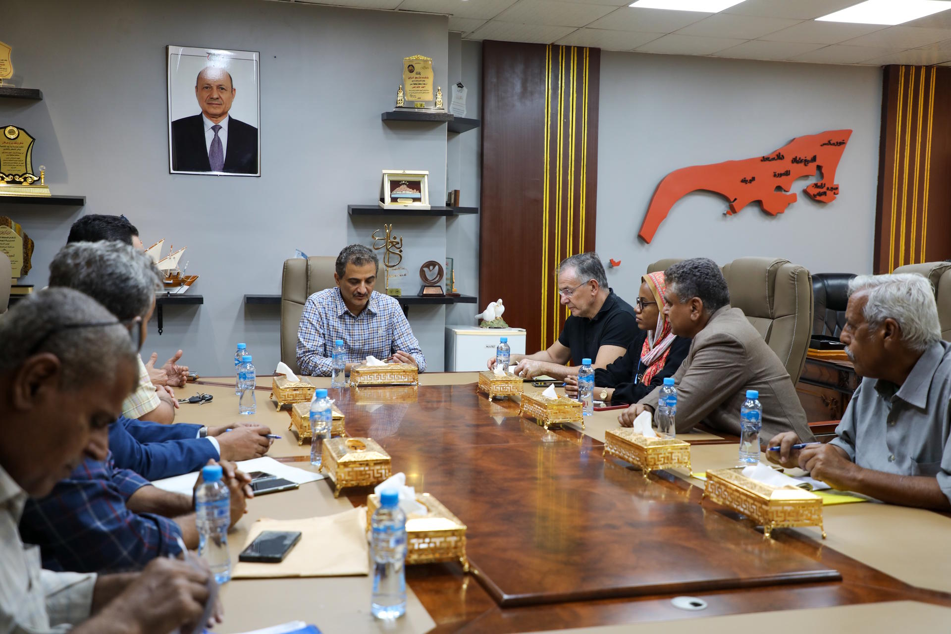 A group of people seated around a conference table in a meeting room, discussing.