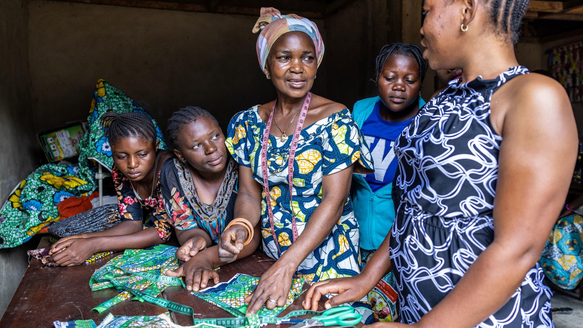 Four women and a girl engaged in crafting activities together in a vibrant workspace.