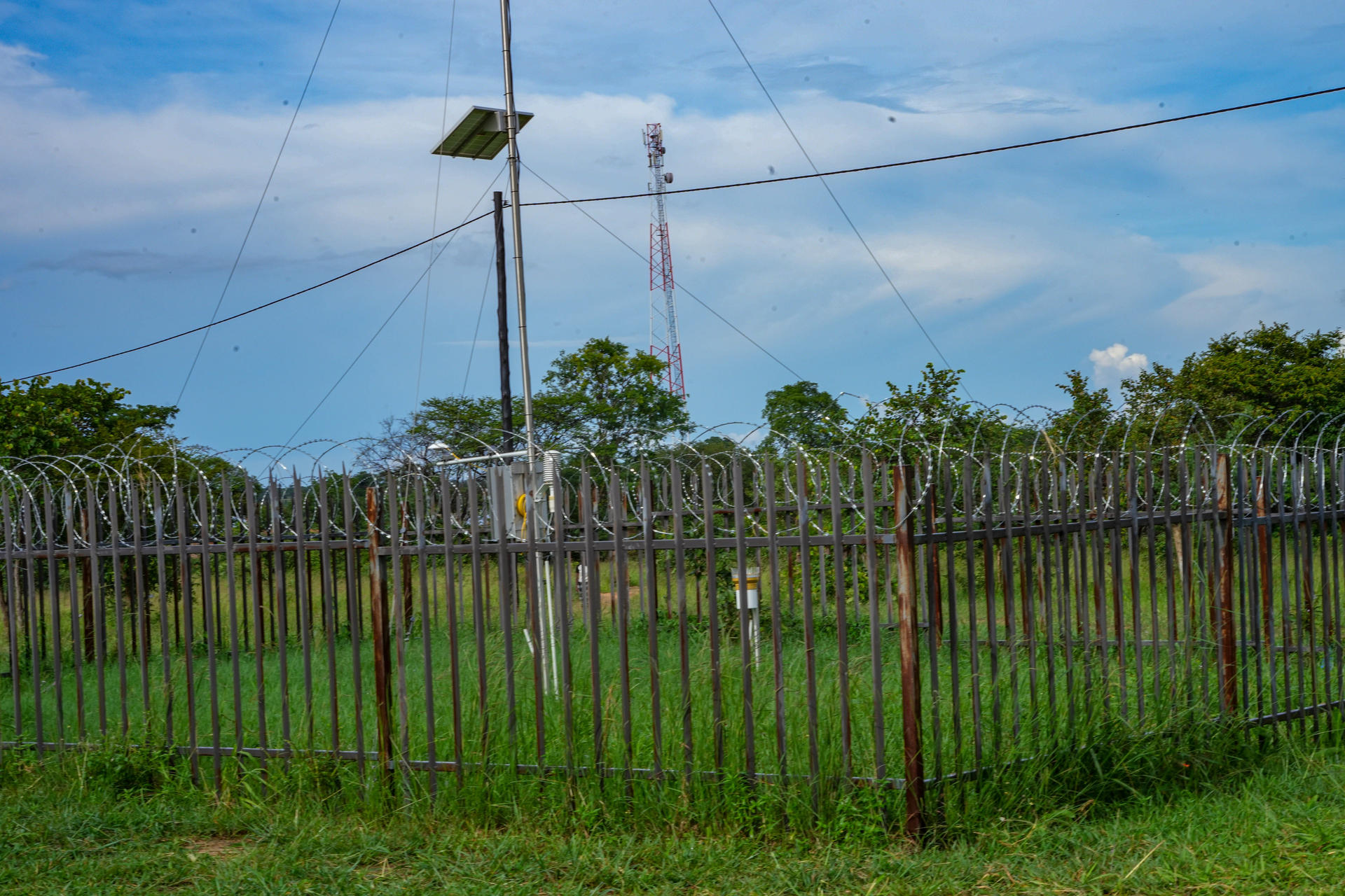 A fenced automatic weather station under a blue sky.
