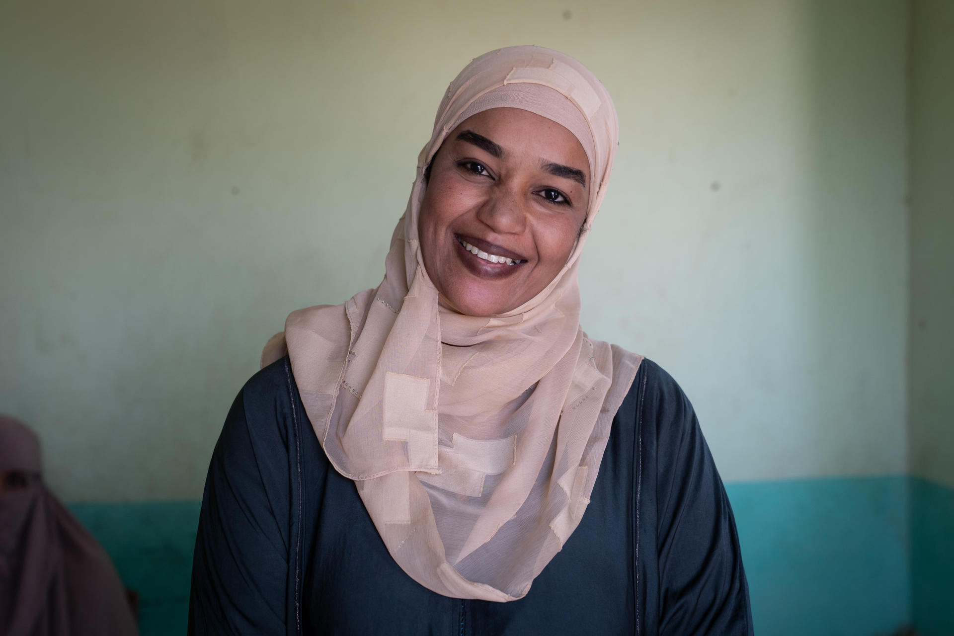 Smiling woman stands in a room with green walls.