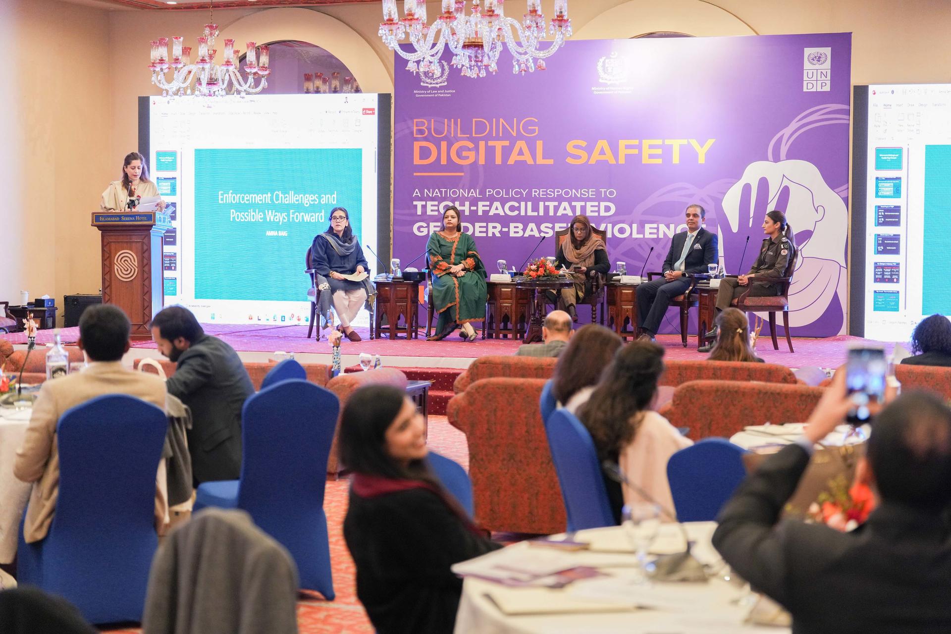 A panel discussion on digital safety, featuring five speakers in formal attire.