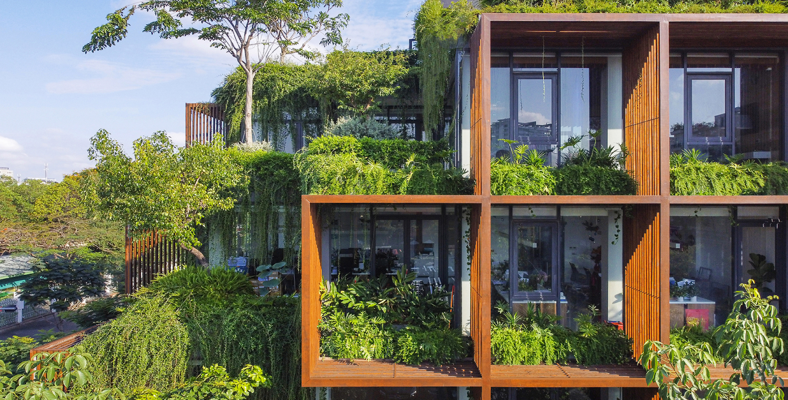 Modern building with lush greenery on multiple levels, overlooking a scenic landscape.