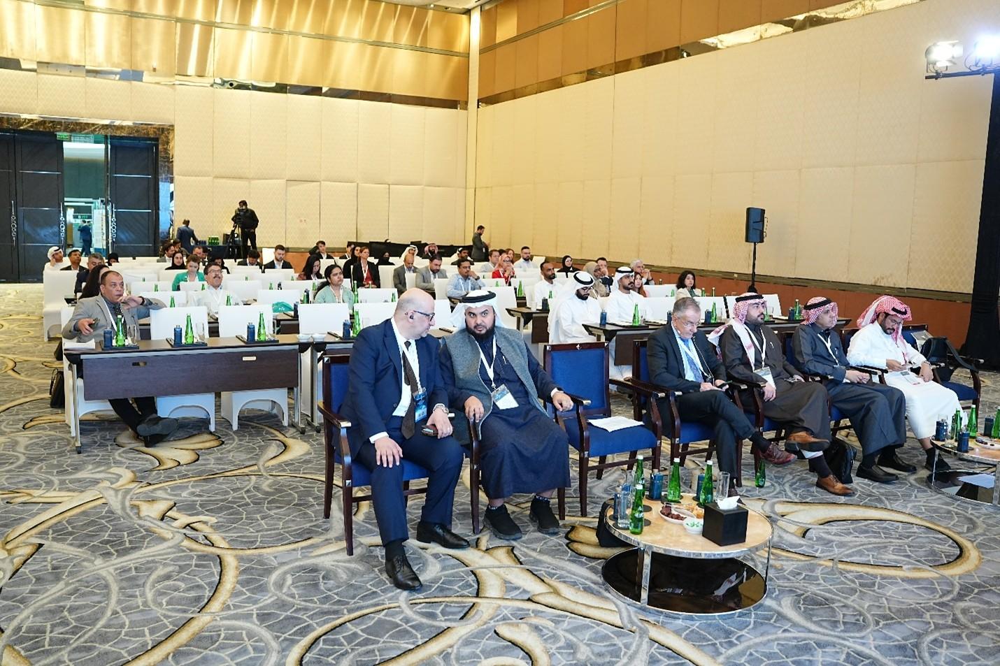 Audience members seated in a conference hall, engaged in a presentation.