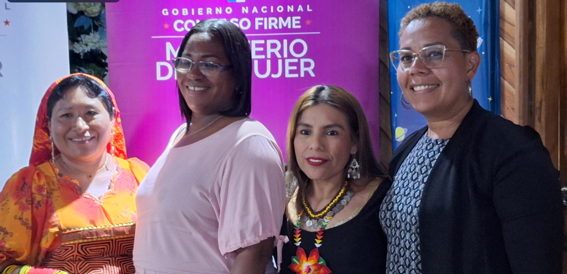 Cuatro mujeres de diferentes etnias permancen de pie frente a un banner