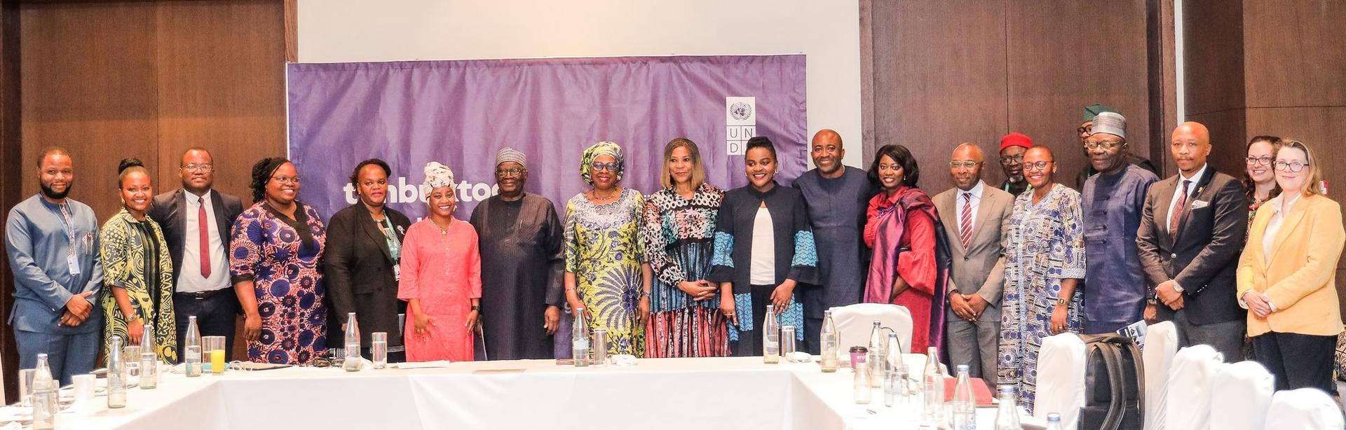 Group of diverse individuals standing together in a conference room, smiling.