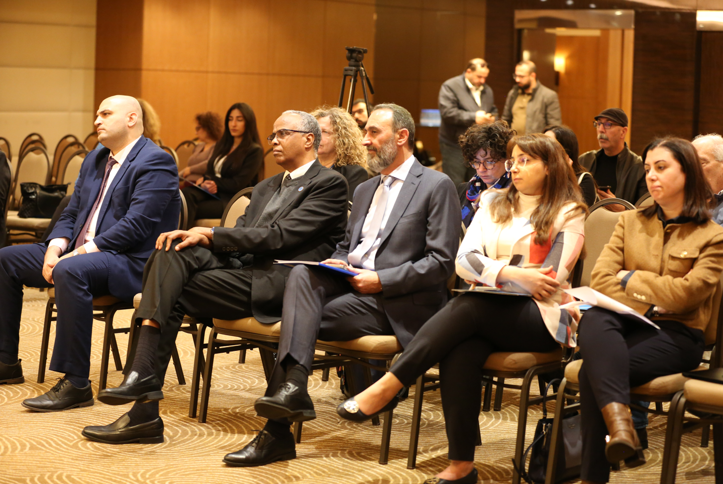 A group of people sitting in a conference room, attentively listening.