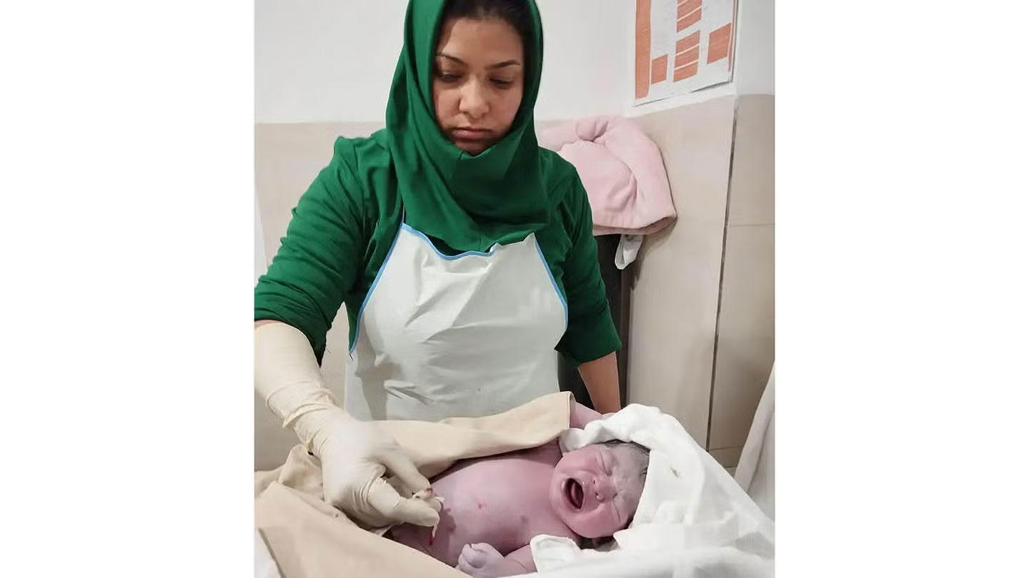 A midwife from the Taiwara Family Health House cleans up a newborn baby.