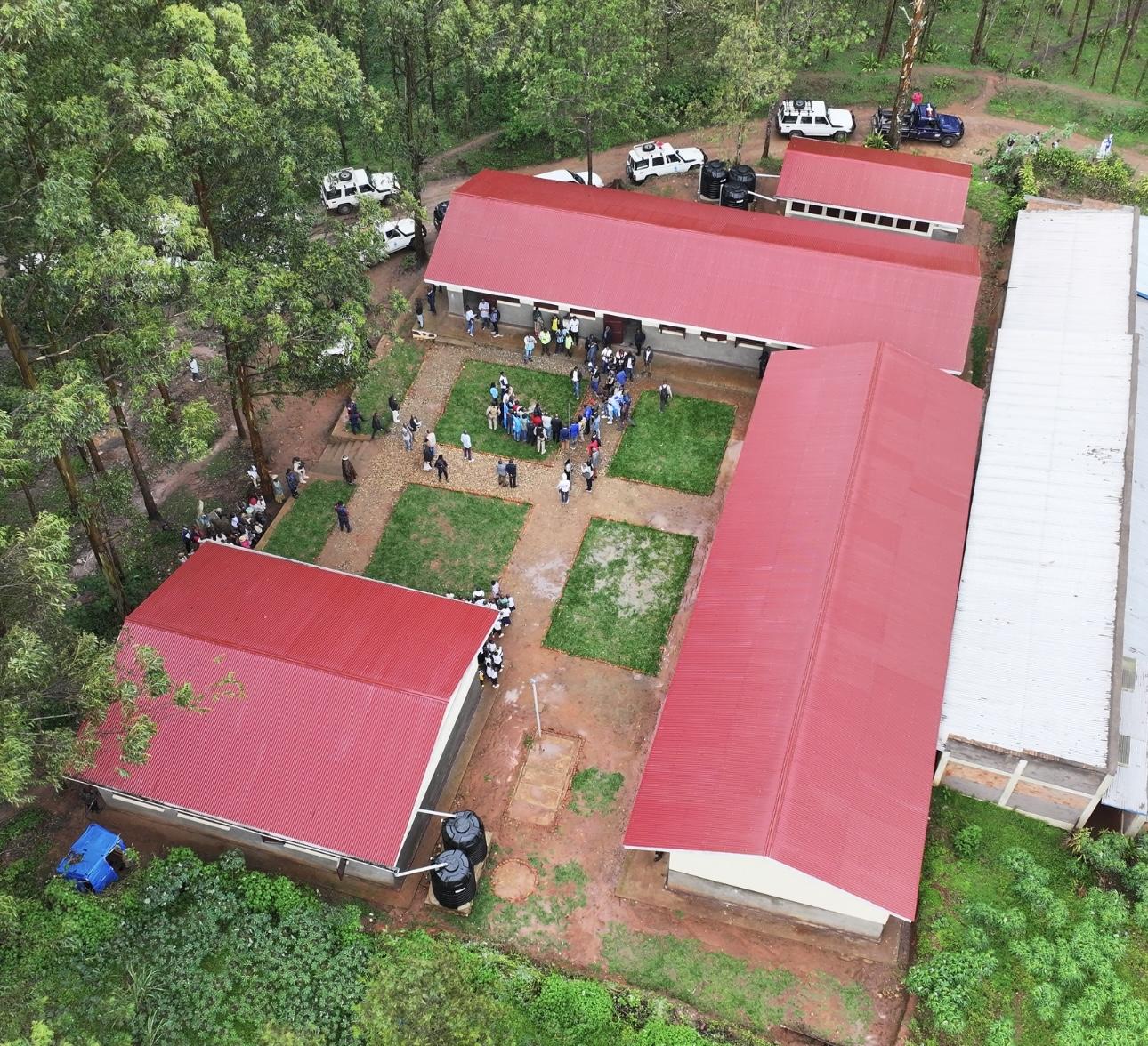 Aerial view of a rural facility with red-roofed buildings and a gathering of people.