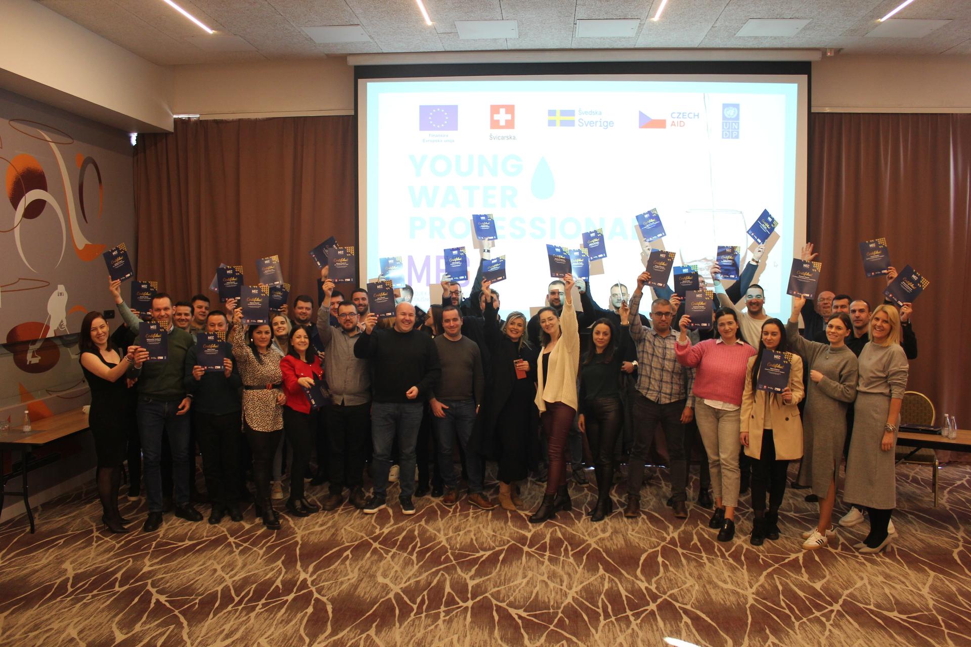 Group of diverse individuals holding blue folders, smiling in a conference setting.