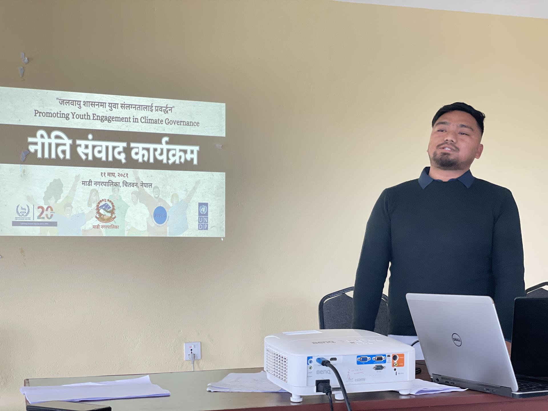 A man stands in front of a projector, giving a presentation in a meeting room.