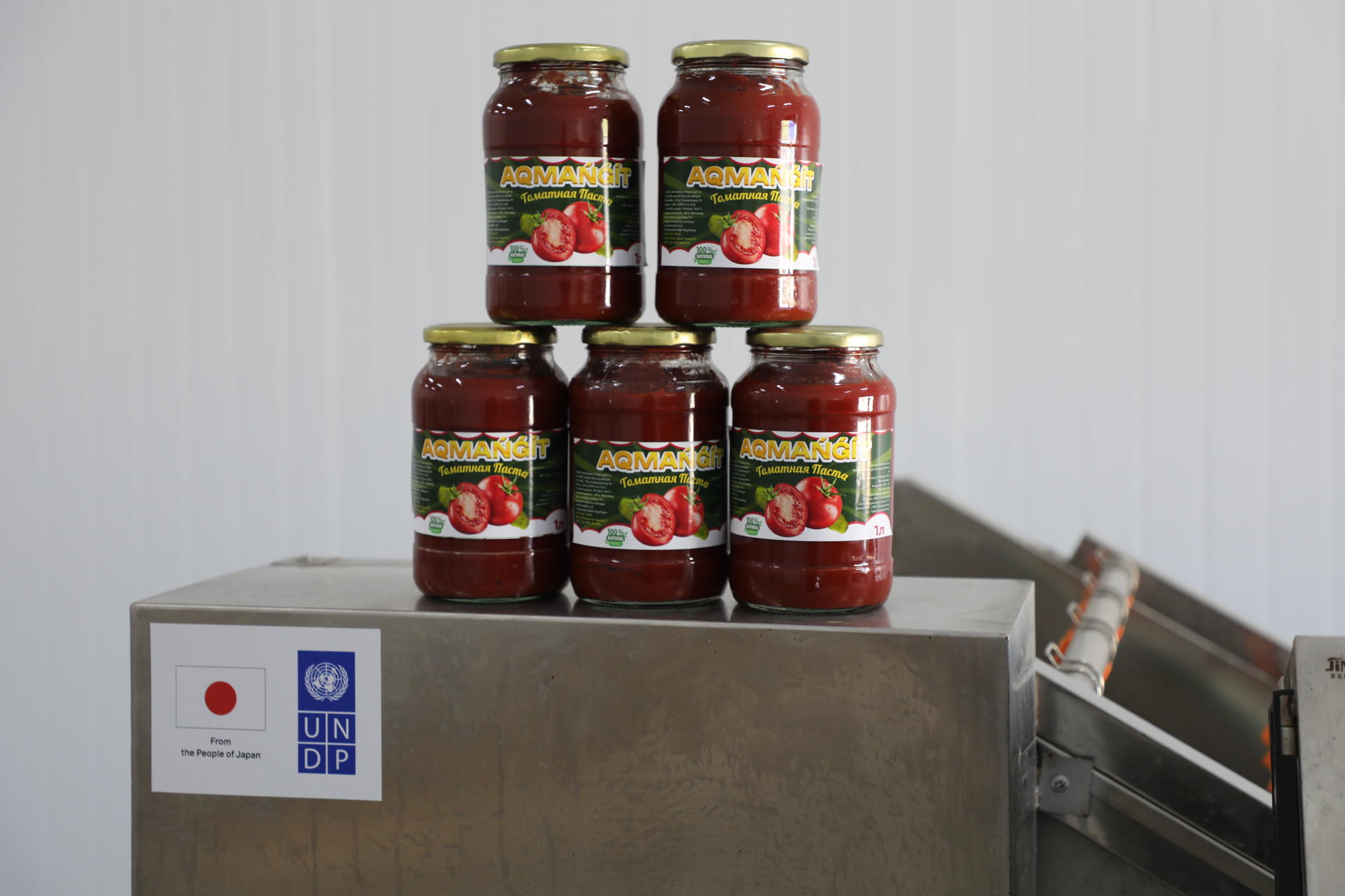 Five jars of tomato sauce stacked on a metallic surface.