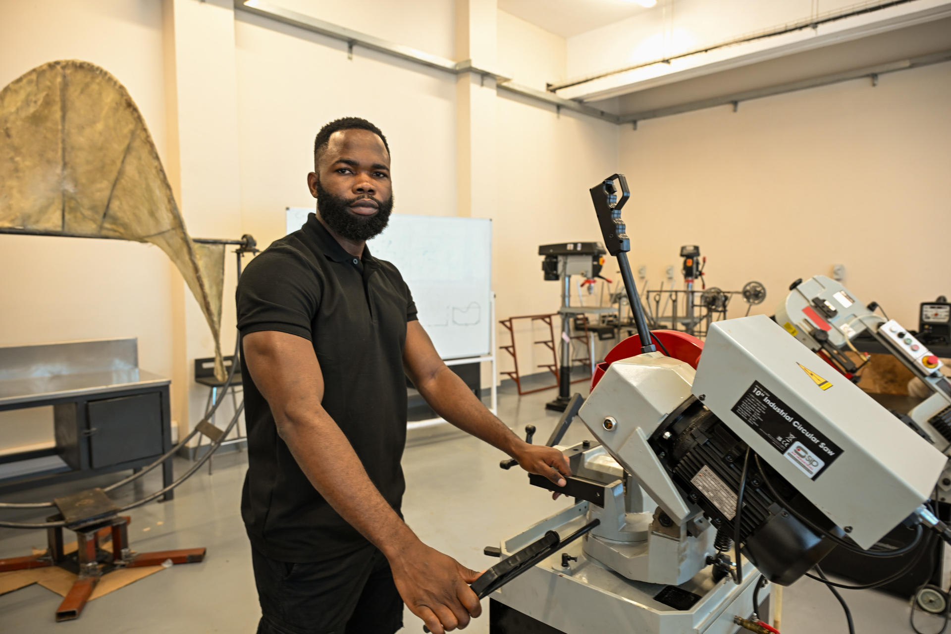 A man in a black shirt operates machinery in a well-lit workshop.