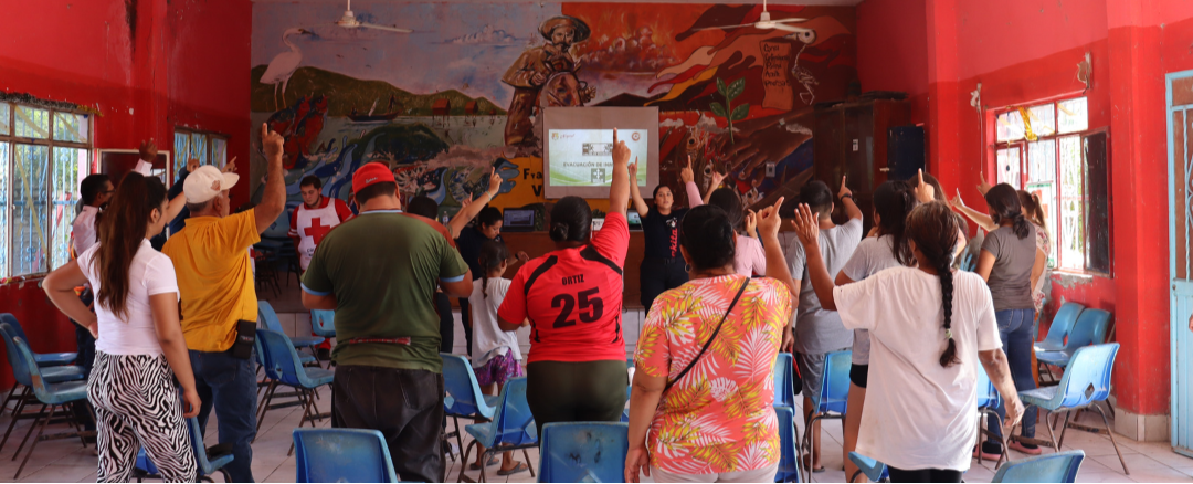 A group of people raising their hands in a brightly colored room with murals.