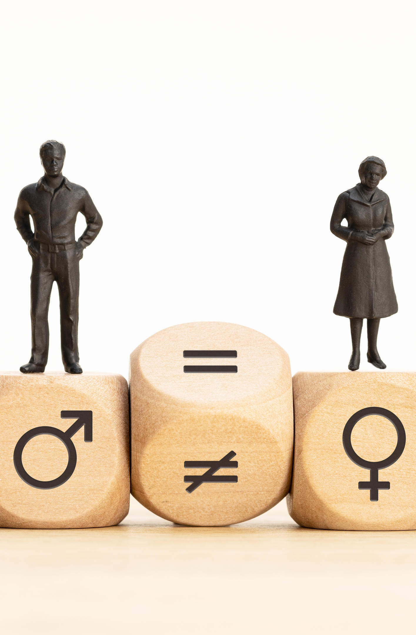 Two figurines representing male and female gender symbols on wooden blocks showing inequality.