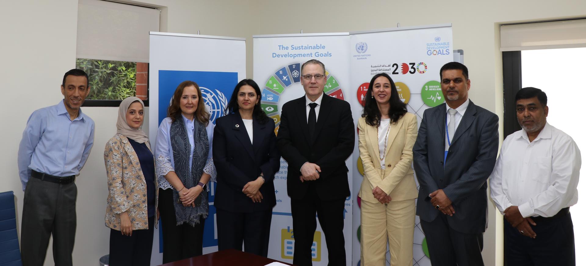 Group of professionals standing together in an office setting, smiling at the camera.