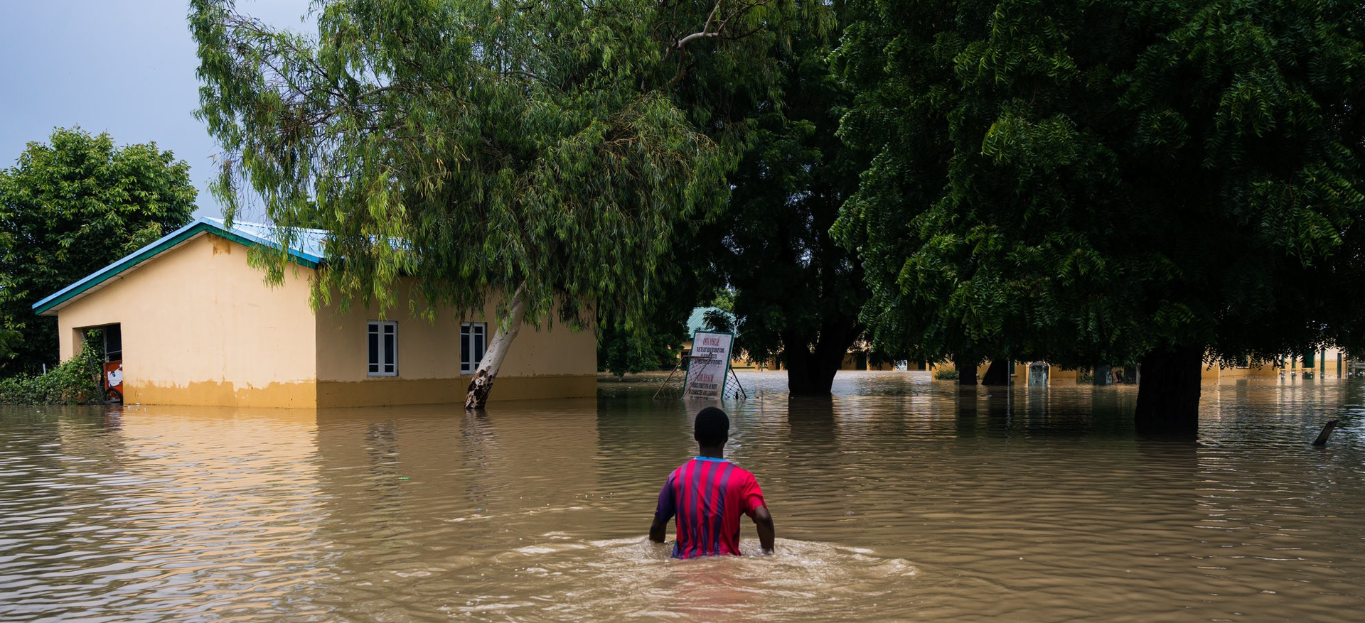 A person wades through floodwaters in Maiduguri Nigeria