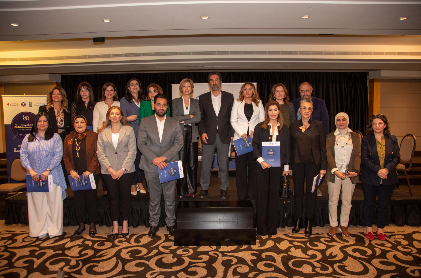 Group photo of 17 people, standing together on stage with certificates in a formal setting.