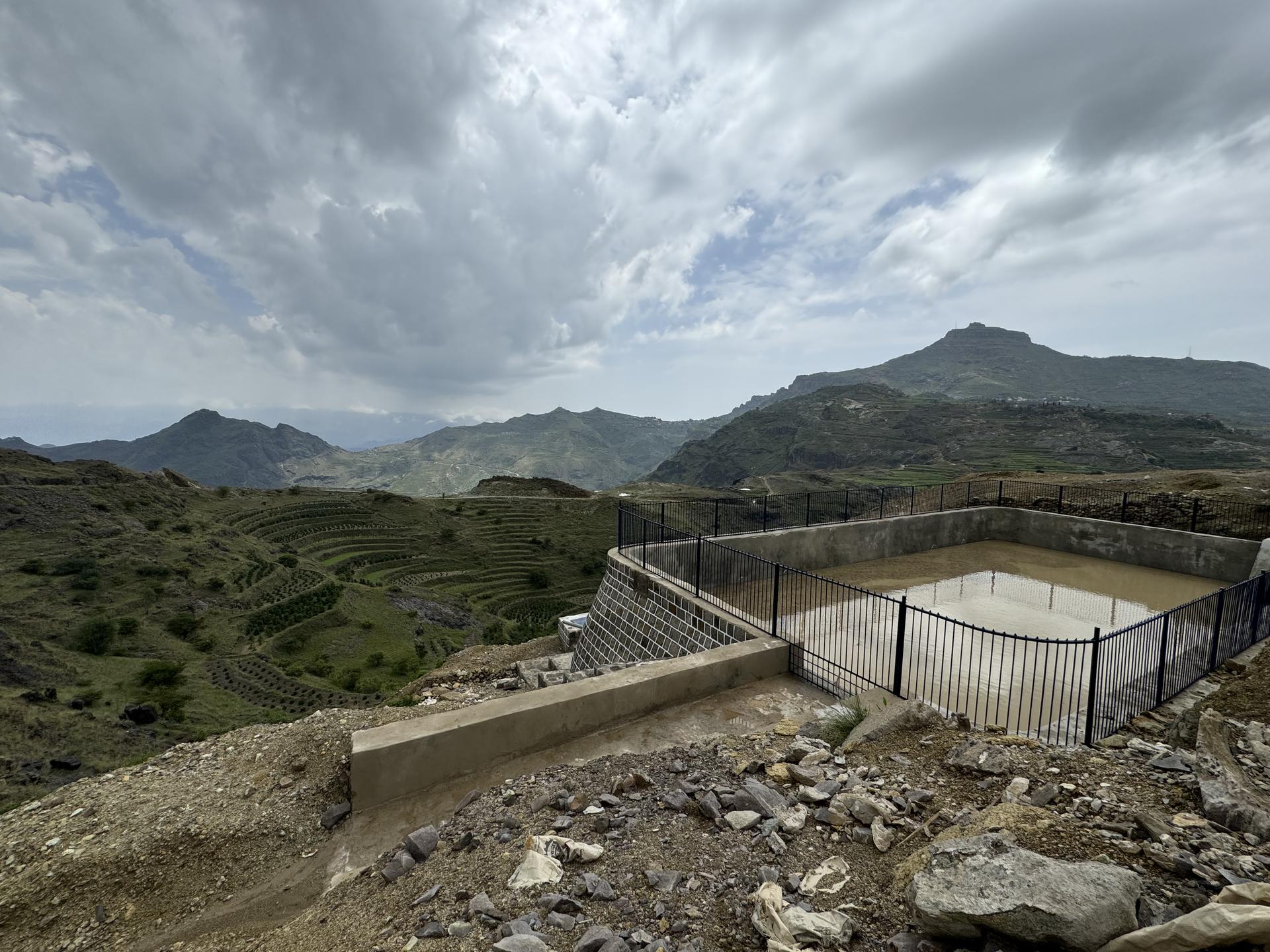 Overlook platform on a rocky hillside, with rolling hills and cloudy sky in the background.