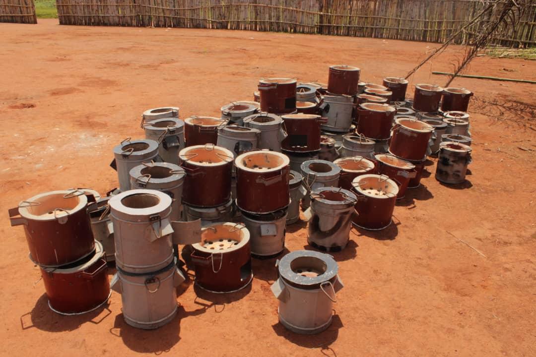 A collection of clay cooking pots arranged on a reddish-brown dirt surface.