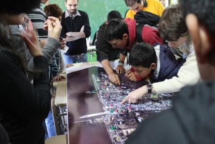 Students and adults gathered around a large map, engaging and pointing at various locations.