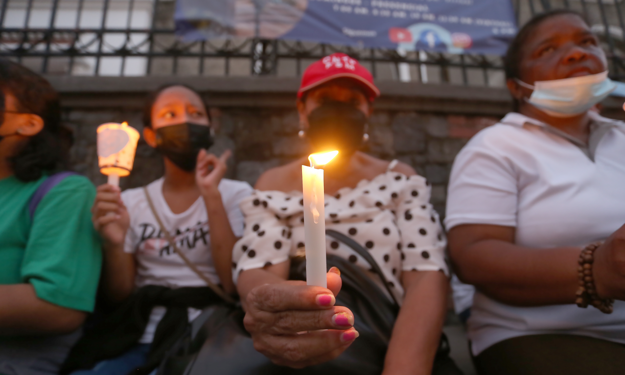 Un grupo de personas sostiniendo velas y utilizando mascarillas.