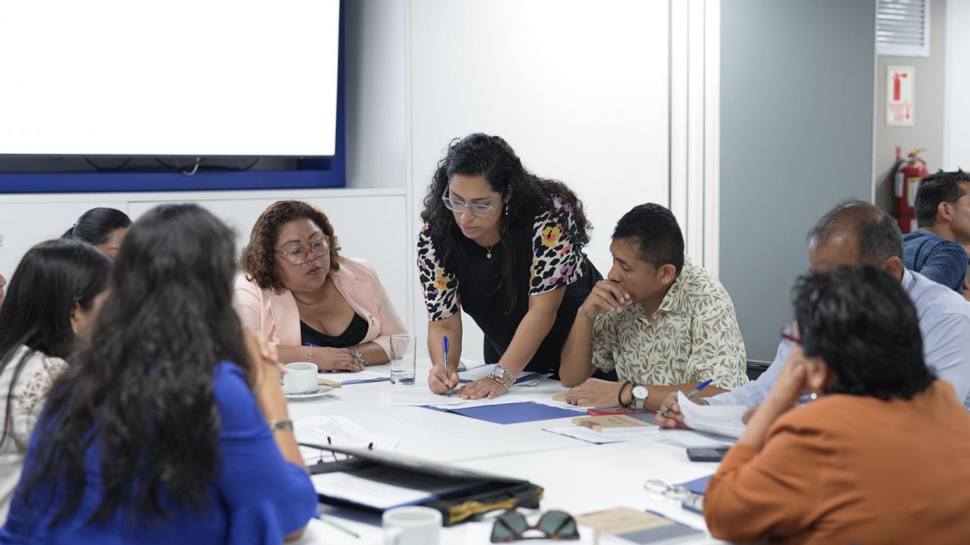 A group of diverse people engaged in a collaborative meeting around a table.