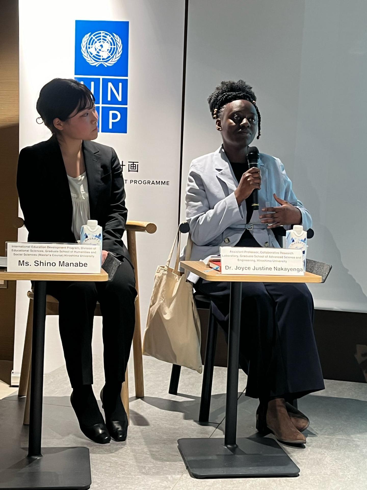 Two women speak at a conference, with one holding a microphone and discussing.