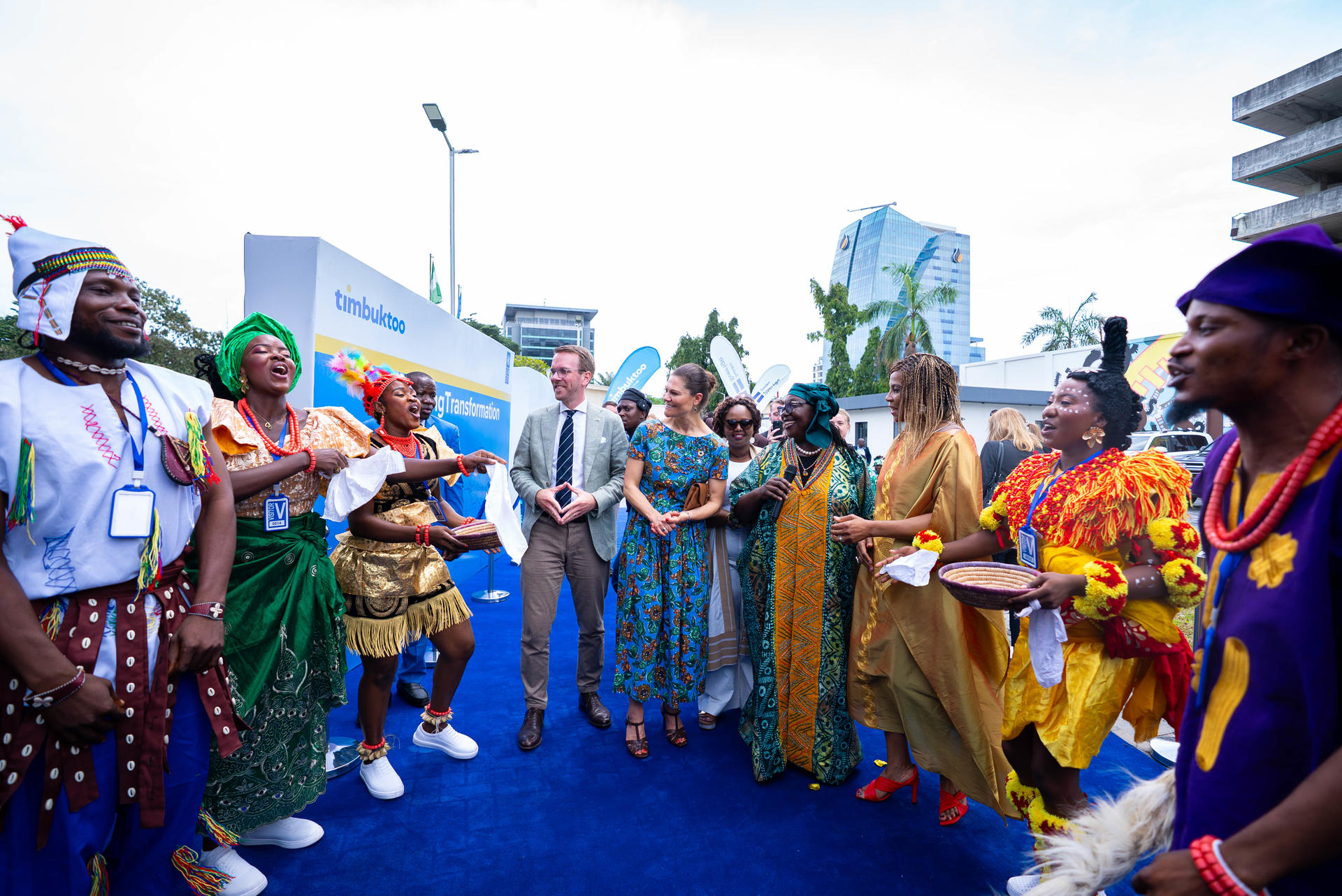 A diverse group of people in colorful traditional attire gathered outdoors, engaging in conversation.