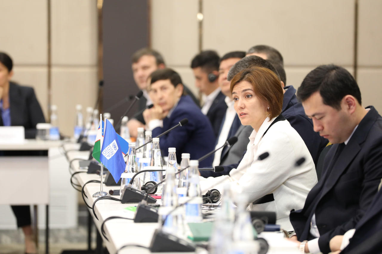 A group of officials engaged in discussion around a conference table.