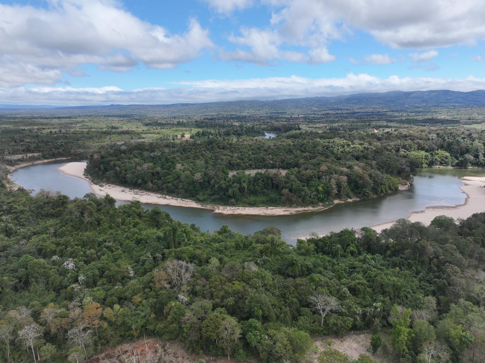 Aerial view of a winding river surrounded by lush green forest and blue sky.