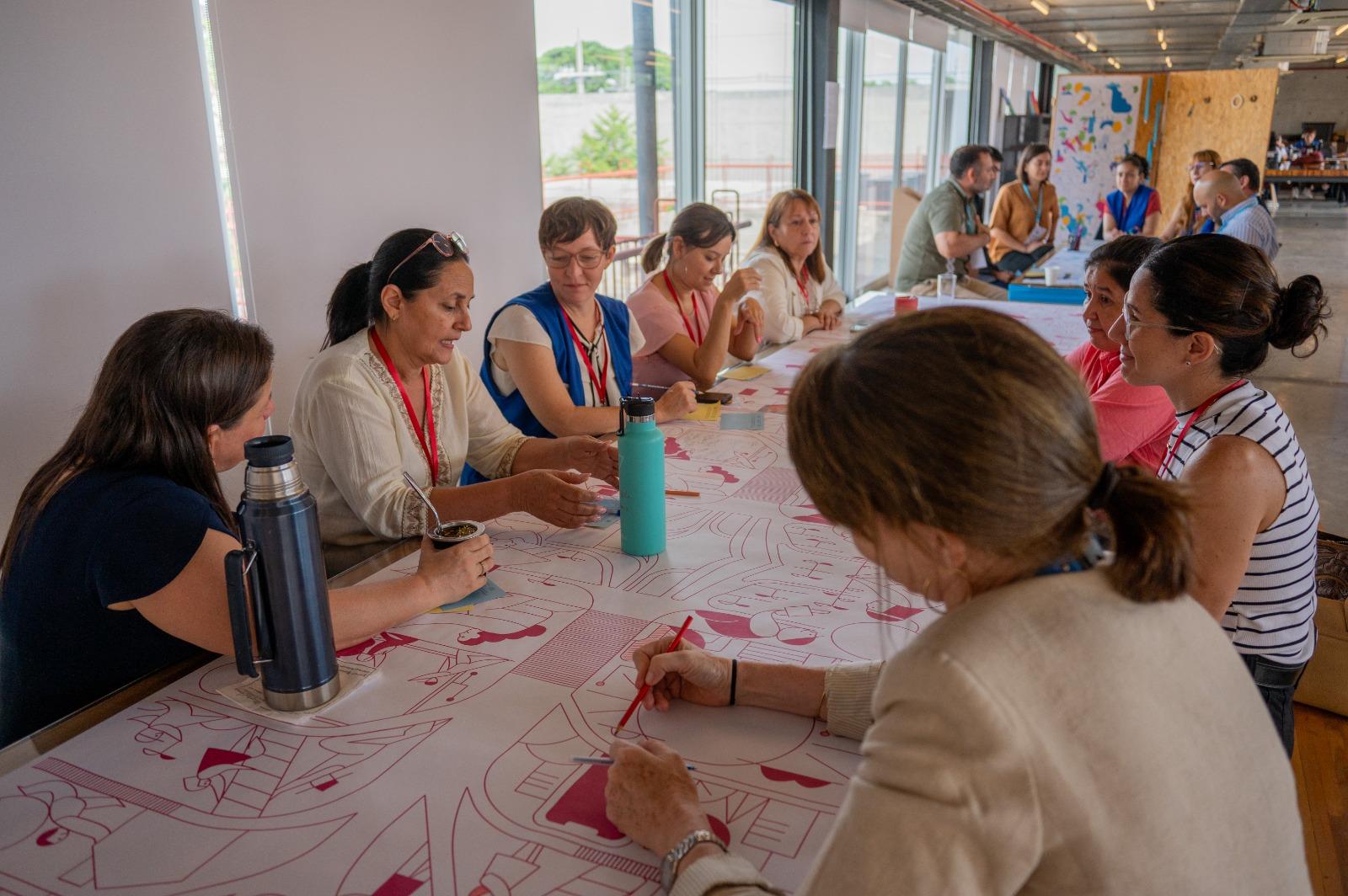 A group of diverse women engaged in a collaborative workshop around a large table.