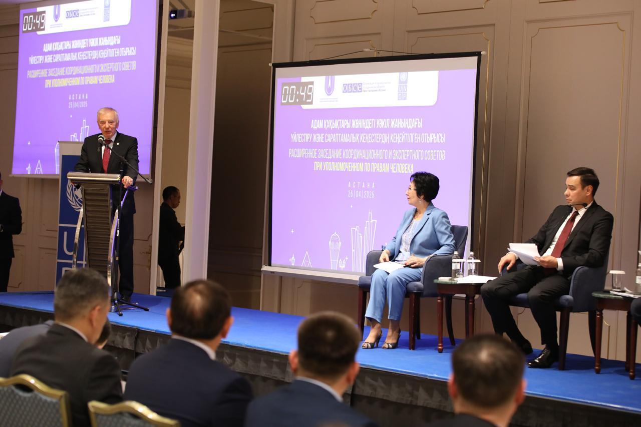 A speaker at a podium addresses an audience during a conference panel discussion.
