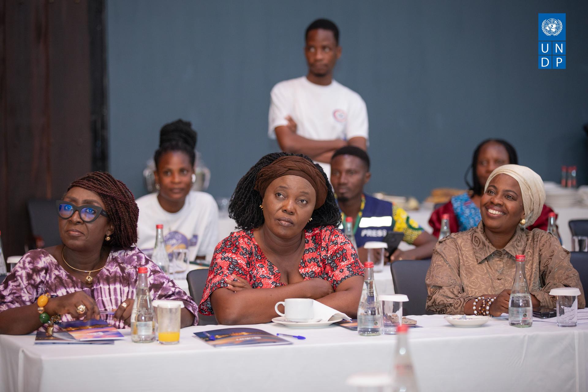 Four people seated at a table during a seminar, with attentive expressions and drinks present.