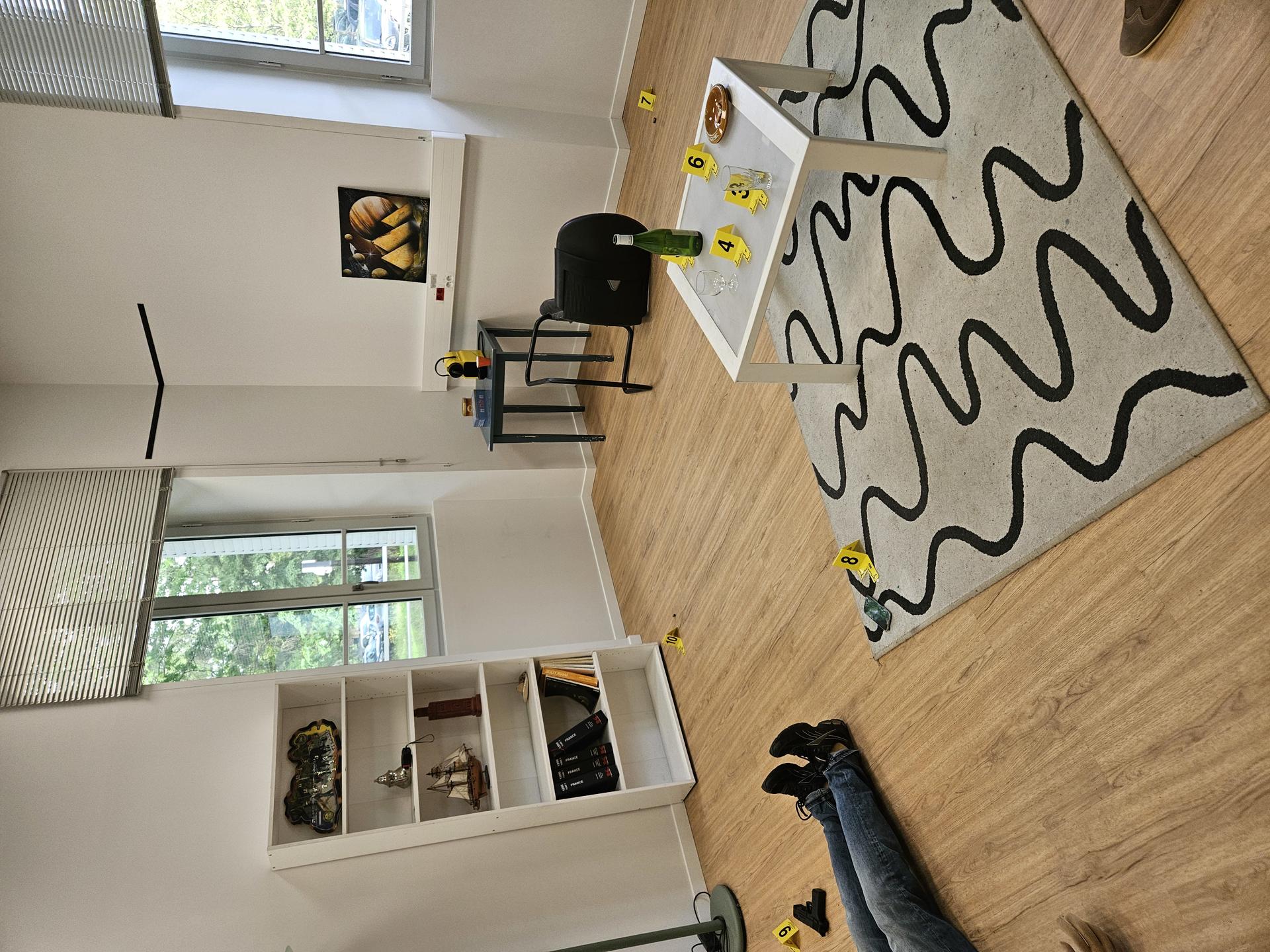 A bright, modern room with hardwood floors, a patterned rug, a chair, and scattered yellow objects.