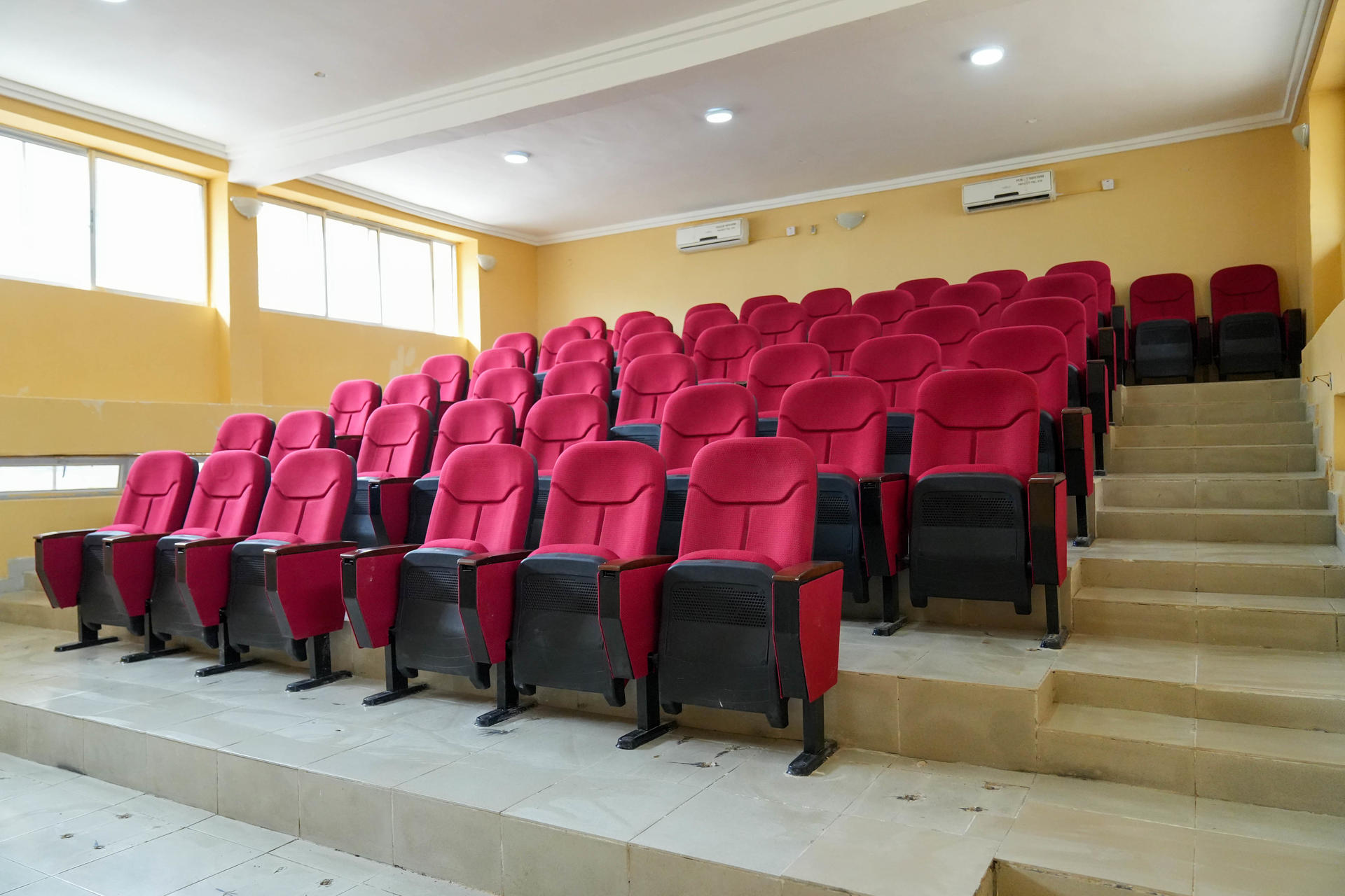Red theater seats arranged in rows inside a brightly lit auditorium.